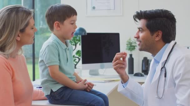 Male Doctor Wearing White Coat Examining Boy Looking Mouth Throat — Stock Video