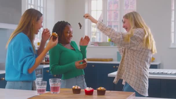 在厨房里 一群文化多元的少女朋友一边吃着纸杯蛋糕 一边把它们挂在彼此的脸上 动作缓慢 — 图库视频影像