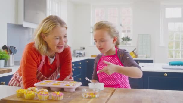 Großmutter Mit Enkeltochter Verziert Selbstgebackene Cupcakes Auf Der Heimischen Küchentheke — Stockvideo