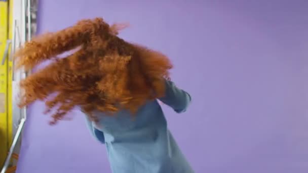 演播室里拍摄的红头发姑娘在紫色背景下打转笑的镜头 动作缓慢 — 图库视频影像