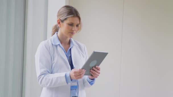 女医生穿着白色外套站在医院走廊里看着数字平板镜头慢镜头 — 图库视频影像
