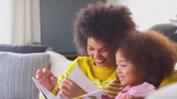 Дочка Сидить Дивані Вдома Матір Читає Книгу Разом Знімається Повільному — стокове відео