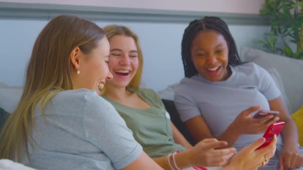 多文化の十代の女の子の友人のグループは 自宅でベッドルームにぶら下がっソファに座っている携帯電話を見て スローモーションで撮影 — ストック動画