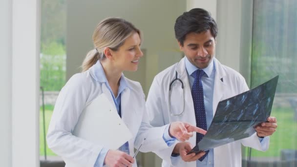 MriやCtスキャンを見て病院の廊下で白いコート会議を着て男性と女性医師 スローモーションで撮影 — ストック動画