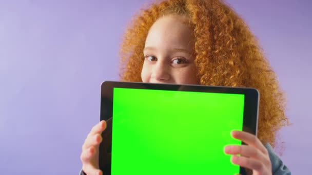 スタジオショットの笑顔の女の子保持デジタルタブレットで緑の画面を見ながらカメラで紫のスタジオの背景 スローモーションで撮影 — ストック動画