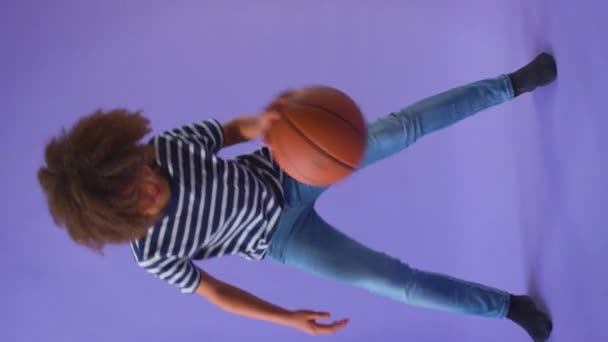 Вертикальное Видео Мальчик Капает Баскетболом Фиолетовом Фоне Студии Снято Замедленной — стоковое видео