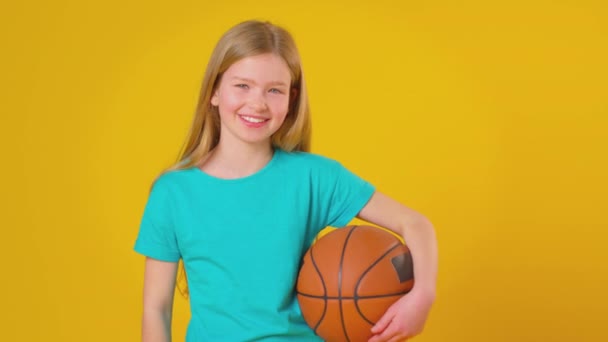 Studyjne Ujęcie Uśmiechniętej Dziewczyny Trzymającej Koszykówkę Pod Pachą Patrzącej Kamerę — Wideo stockowe
