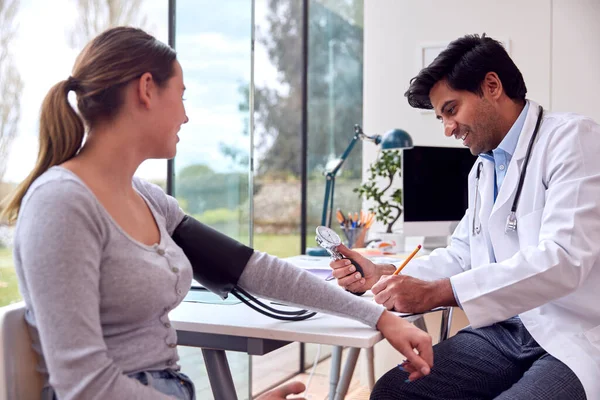 Male Doctor Examining Teenage Girl Taking Blood Pressure Sphygmomanometer — Stockfoto