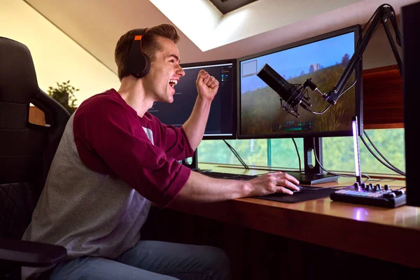 Excited Man Gaming Home Wearing Wireless Headphones Sitting Desk Multiple — Stockfoto