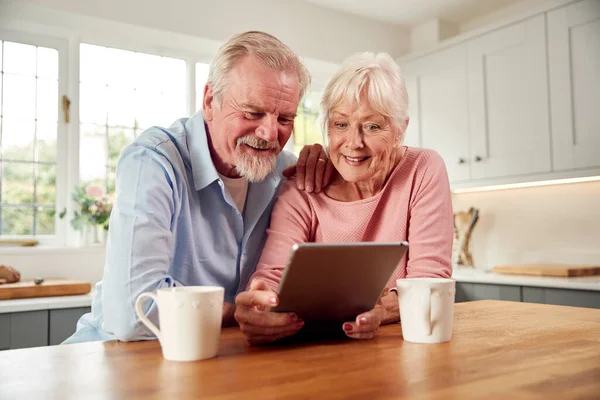 Retired Senior Couple Sitting Kitchen Home Drinking Coffee Using Digital — Stockfoto