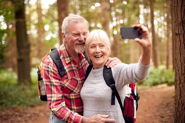 Retired Senior Couple Posing Selfie Mobile Phone Hiking Woodland Countryside — Stockfoto