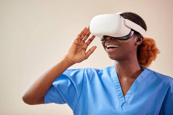 Female Nurse Or Doctor In Scrubs With VR Headset Interacting With AR Technology