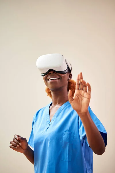 Female Nurse Or Doctor In Scrubs With VR Headset Interacting With AR Technology