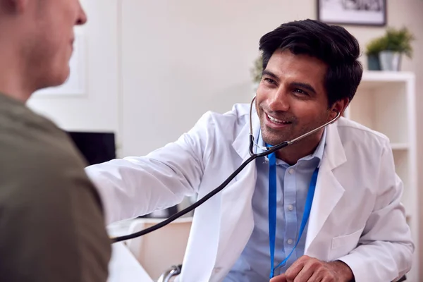 Male Doctor Wearing White Coat Examining Young Man Listening Chest — Stockfoto