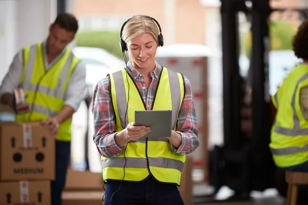デジタルタブレットを使用した物流倉庫のヘッドセットを身に着けている女性労働者 — ストック写真