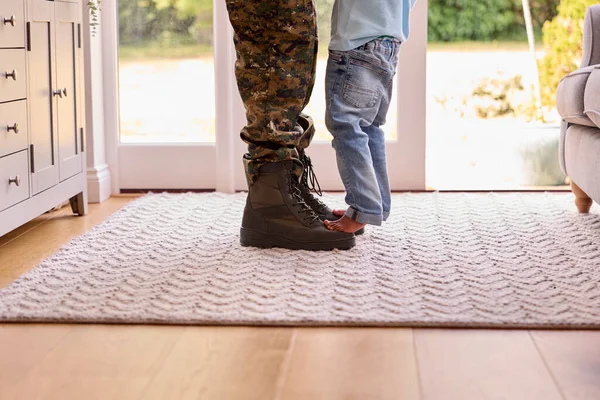 Close Up Of Loving Army Father In Uniform Home On Leave With Son Standing On Feet