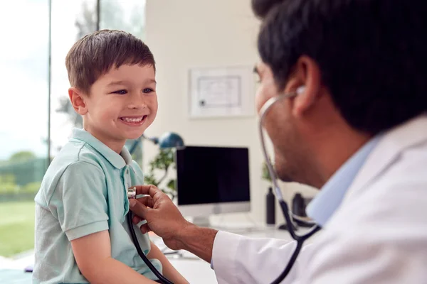 Male Doctor Wearing White Coat Examining Smiling Boy Listening Chest — Stockfoto