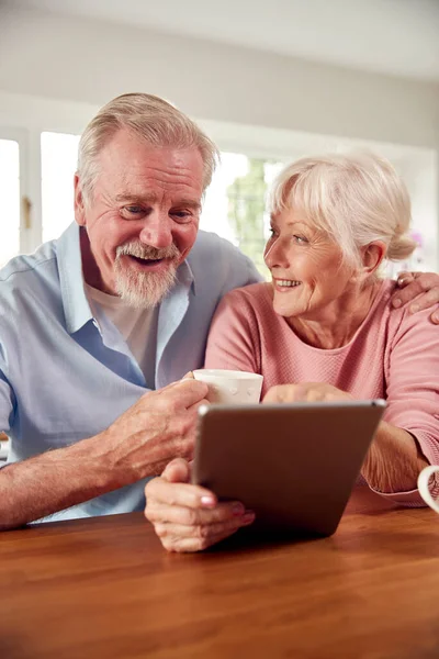 Retired Senior Couple Sitting Kitchen Home Drinking Coffee Using Digital — Φωτογραφία Αρχείου