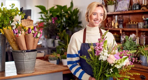 Female Owner Of Florists Shop Arranging Bouquet Of Flowers