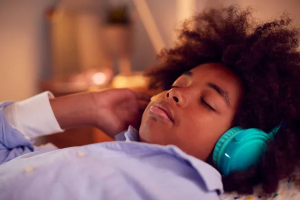 Boy Lying On Bed Wearing Wireless Headphones With Eyes Closed Listening To Music Or Audiobook