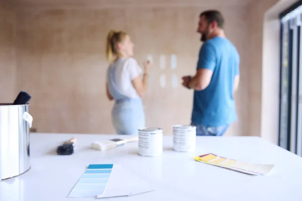 家庭用塗料テスターでキッチンを改装したカップルとして前景に焦点を当てる壁にペイントカラーストリップ — ストック写真