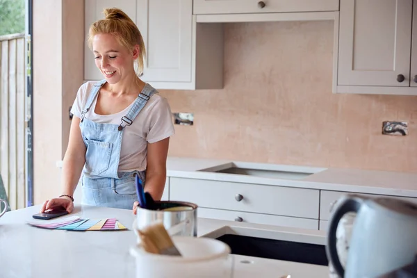 Mulher Renovando Cozinha Casa Com Amostras Tinta Usando Telefone Móvel — Fotografia de Stock
