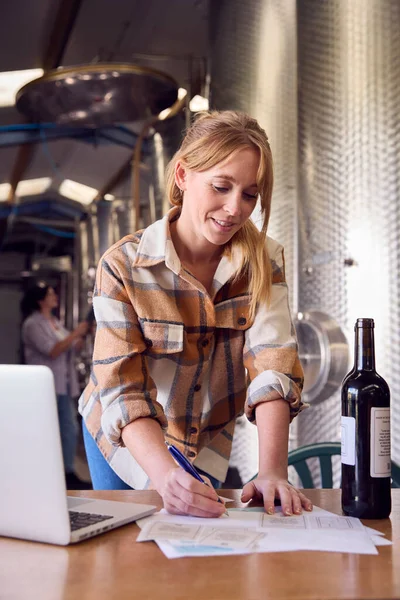 Vrouw Met Laptop Maken Notities Door Fles Label Binnen Wijnmakerij — Stockfoto
