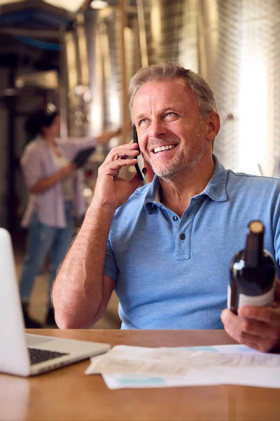 Mature Man Mobile Phone Laptop Checking Label Bottle Winery — Stock Photo, Image
