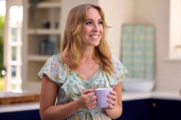 微笑的女人站在厨房里喝着一杯咖啡放松一下 — 图库照片
