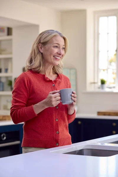 Gülümseyen Olgun Bir Kadın Mutfakta Kahve Fincanıyla Dinleniyor — Stok fotoğraf
