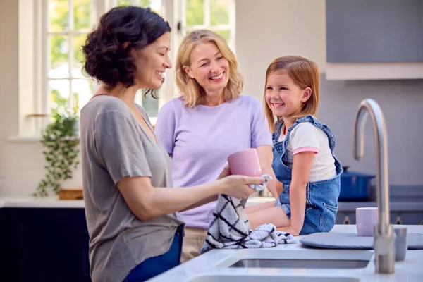 同性家庭与两个成熟的母亲和女儿一起在厨房洗碗 — 图库照片