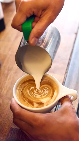 バリスタの終わりカフェでコーヒーにミルクを入れて泡アートの装飾を作る — ストック写真
