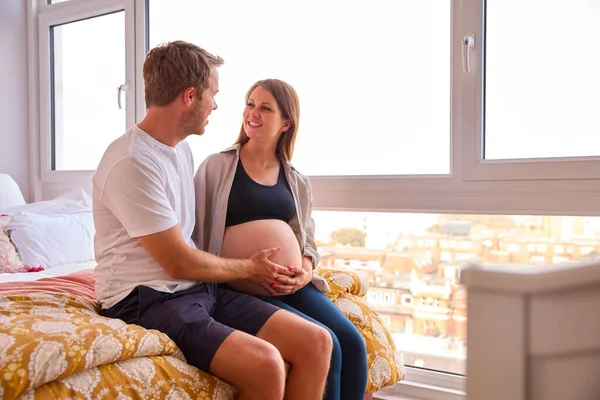 自宅でカップルを愛します男とベッドの上で座っている妊娠中の女性の胃に触れる — ストック写真