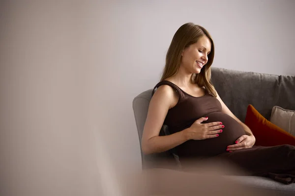 Беременная Женщина Отдыхает Диване Холдинге Живот — стоковое фото