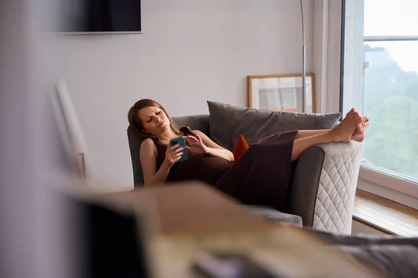 孕妇带着手机在家里的沙发上放松 — 图库照片