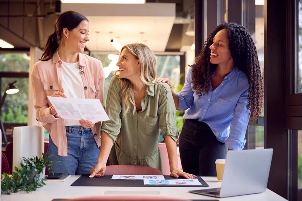 女性ビジネスチームがオープンプランオフィスのデスクに立ち 校正や設計レイアウトの確認を承認 — ストック写真