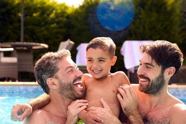 两个父亲的同性家庭和两个儿子一起在游泳池里度假 — 图库照片