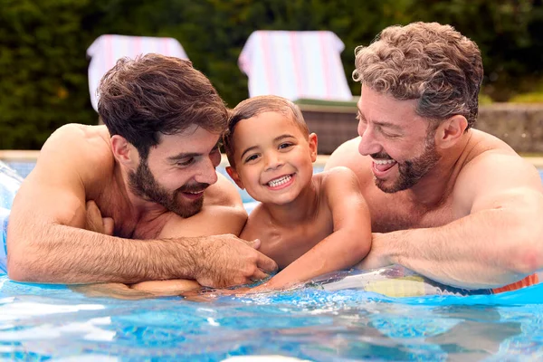 两个父亲的同性家庭和两个儿子一起在游泳池里度假 — 图库照片