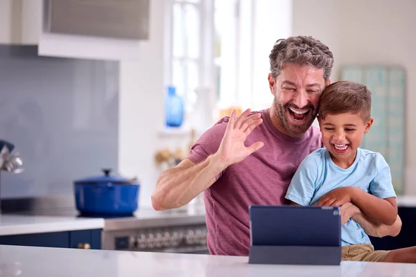 デジタルタブレットでビデオ通話をする息子とキッチンで自宅で成熟したお父さん — ストック写真