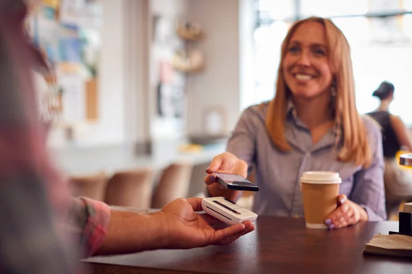 Kobieta Dokonująca Płatności Zbliżeniowej Kawiarni Przy Użyciu Telefonu Komórkowego — Zdjęcie stockowe