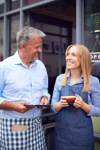 デジタルタブレットでコーヒーショップの外に立つ男性と女性のオーナーやスタッフ — ストック写真