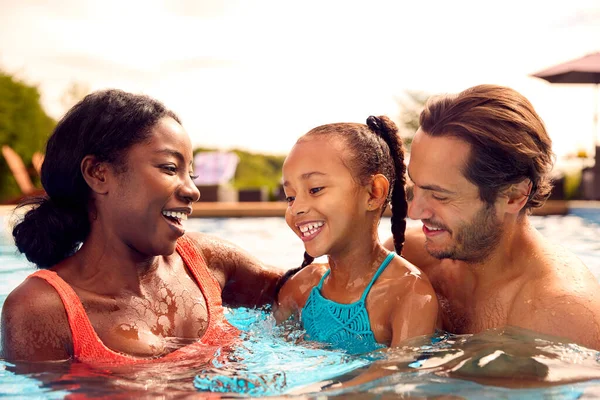 屋外スイミングプールで楽しいスプラッシュを持つ夏休みの笑顔の混合レース家族 — ストック写真