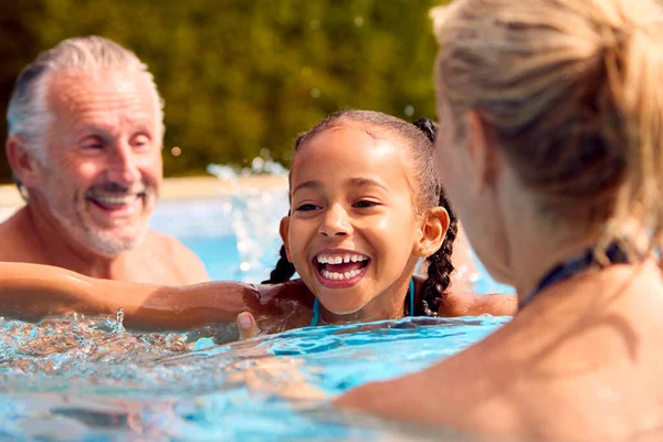 祖父母在游泳池教孙女在家庭暑假游泳 — 图库照片