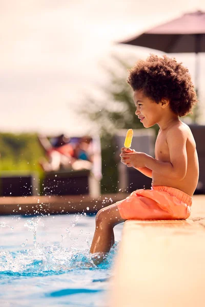 Rodina Letní Dovolenou Chlapcem Jíst Led Lízátko Cákání Okraji Bazénu — Stock fotografie