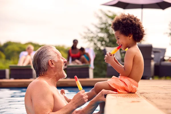 祖父と孫は夏休みにプールの端でアイスロリーを食べる — ストック写真