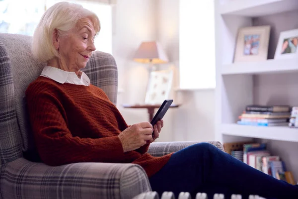 Senior Kvinna Med Mobiltelefon Hålla Värmen Genom Bärbar Radiator Kostnaden — Stockfoto