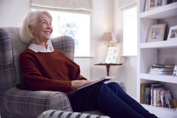 用便携式散热器保暖的老年妇女读物 以生活能源危机为代价 — 图库照片