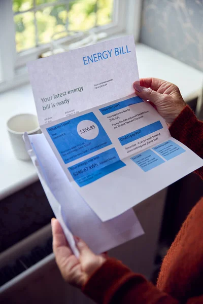 米国のエネルギー法案を持つシニア女性は 生活エネルギー危機のコストで放射線によって暖かくしようとします — ストック写真