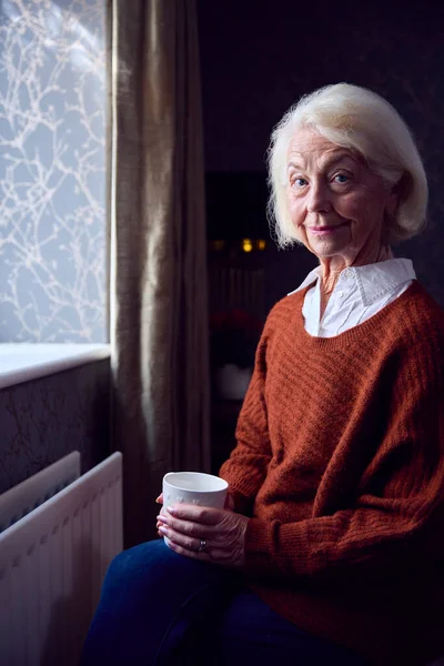 Senior Vrouw Met Warme Drank Proberen Warm Houden Door Radiator — Stockfoto