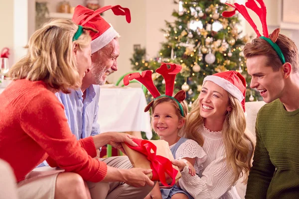 サンタの帽子と釣り人をかぶって自宅でクリスマスを祝う世代の家族がプレゼントを開く — ストック写真